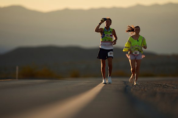 Westergaard, a la izquierda, se enfría con agua con ayuda de su hija Madison Westergaard cuando sale el sol durante el Ultramarathon Badwater 135 el 8 de julio.