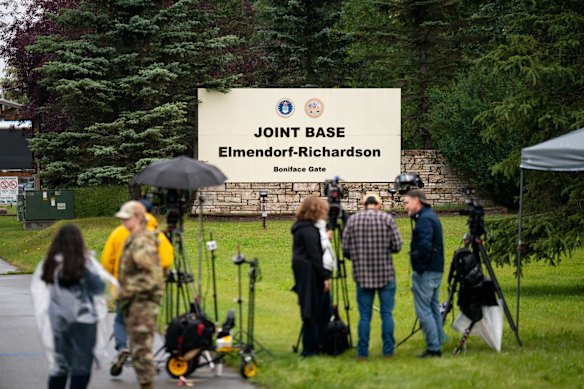 Los miembros de los medios se reunen cerca de la entrada de la base aérea en Anchorage el día antes de la cumbre.