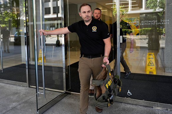 Los agentes del FBI salen de la entrada principal del ex asesor de seguridad nacional de Trump, John Bolton, la oficina de Washington.