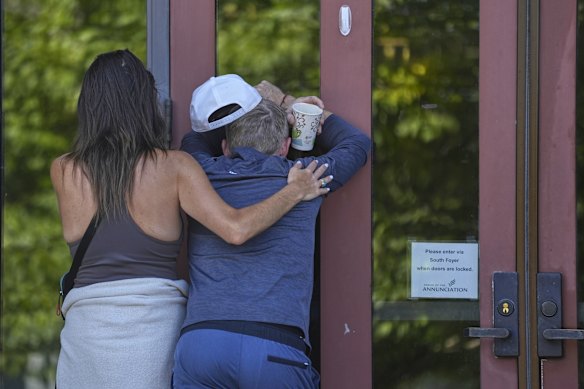 Kristen Neville, a la izquierda, y Michael Burt lloran en las puertas de la iglesia.
