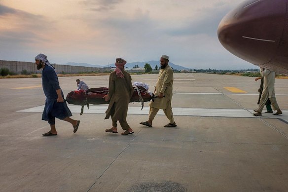 Una víctima del terremoto en una camilla es llevada a una ambulancia en un aeropuerto de Jalalabad.