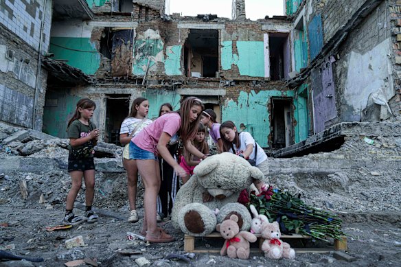 Las chicas limpian el polvo de un oso de peluche frente a una casa destruida por una huelga rusa en Kiev, Ucrania, la semana pasada.