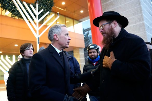 El primer ministro canadiense, Mark Carney, habla con el rabino Chaim Boyarsky en una ceremonia de encendido de la menorá en Ottawa.